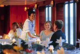 Happy couple being served dinner in an elegantly appointed ship's dining room.